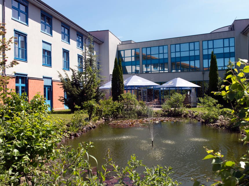Moderner Gebäudekomplex mit Garten und Teich im Vordergrund