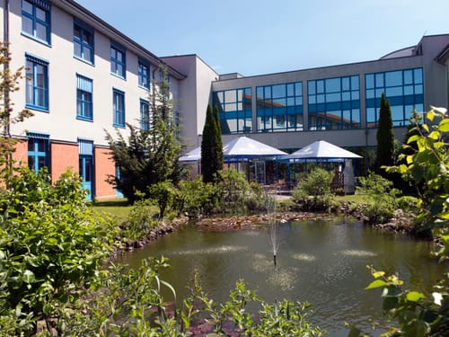 Moderner Gebäudekomplex mit Garten und Teich im Vordergrund