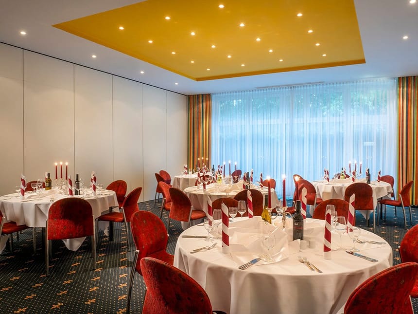 Eleganter Veranstaltungsraum mit festlich gedeckten Tischen und Kerzenlicht