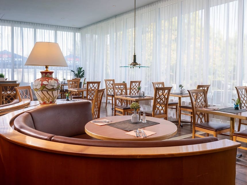 Elegantes Restaurant mit Holzmöbeln und großen Fenstern