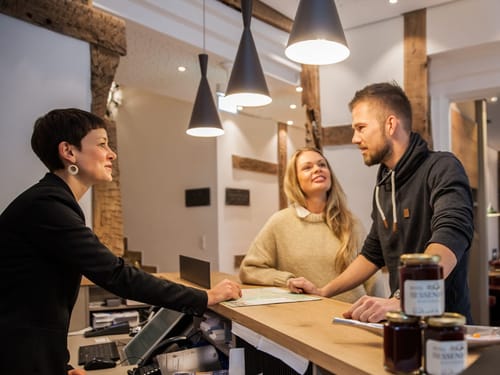 Hotelrezeptionist spricht mit Paar am Empfangstresen