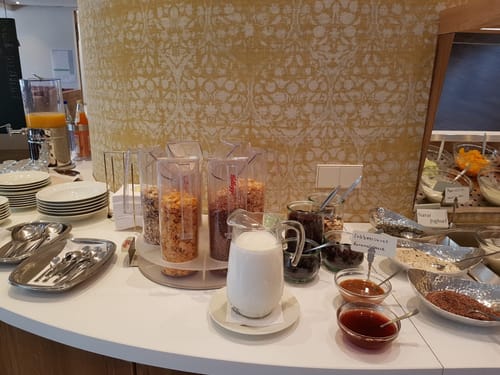 Entdecken Sie unser vielfältiges Frühstücksbuffet mit einer Auswahl an Müslis, frischer Milch und leckerem Obst. Genießen Sie individuell zusammengestellte Schalen mit Erdbeersauce, Karamellsauce und gesunden Toppings.