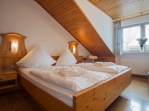 Gemütliches Schlafzimmer in einem Hotel mit Holzmöbeln und Dachschräge.