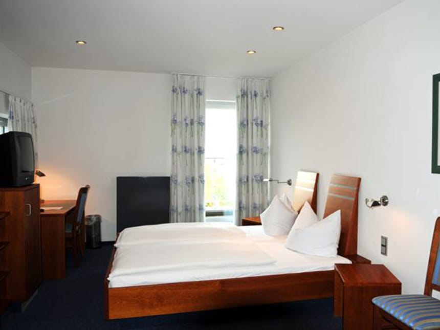 Kleines Zimmer mit einem Fernseh, Schreibtisch und zwei Stühlen