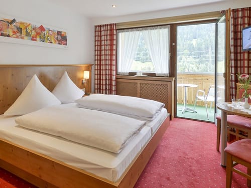 Standard Doppelzimmer mit Doppelbett, TV, Tisch, Stühlen und Balkon