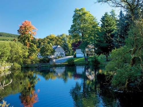 Teich mit Bäumen und dem Hotel im Hintergrund