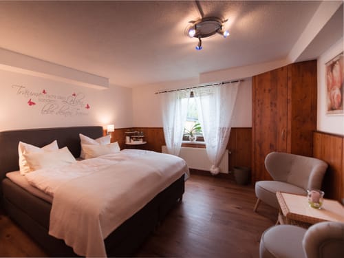 Sauna Doppelzimer mit Doppelbett, Sessel und Tisch