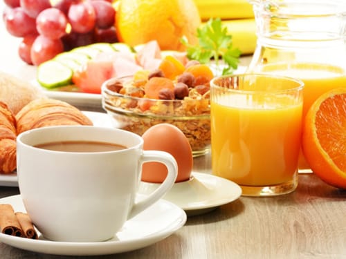 Kaffee, Ei, Saft und Müsli auf dem Frühstückstisch