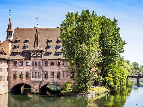 Häuser an der Pegnitz am Fluss, umgeben von großen Bäumen