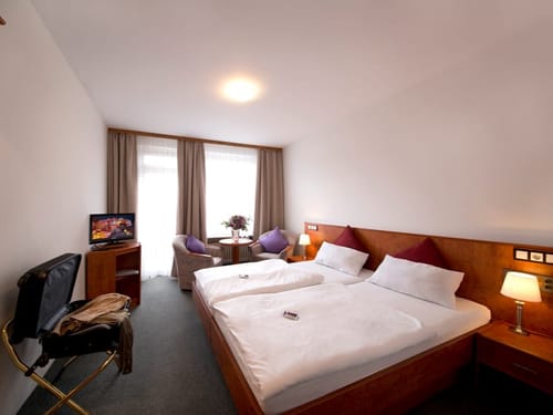 Komfortables Hotelzimmer mit Doppelbett, Fernseher und Sitzbereich