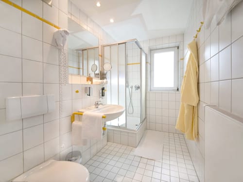Modernes Badezimmer mit Dusche und weißen Fliesen