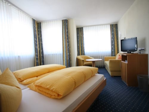 geräumiges Doppelzimmer mit Doppelbett, Sesseln, Tisch und TV