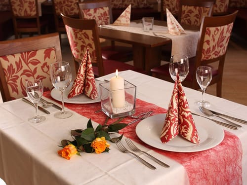 gedeckter Tisch mit Wein und Wasserglas, Tellern, Besteck und Deko