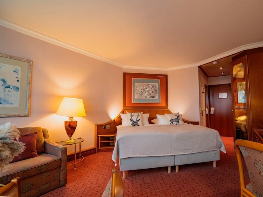 Doppelzimmer Domizil mit Boxsringbett, Sessel, Schreibtisch, Stuhl und Couch