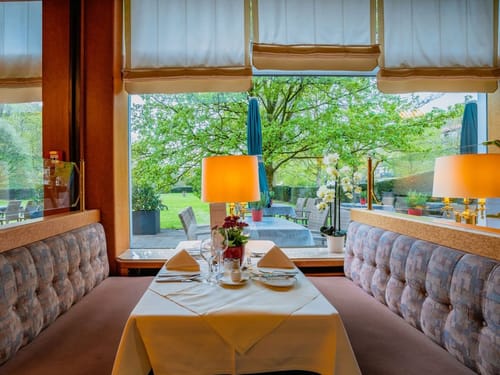 festlich gedeckter Tisch im Restaurant mit herrlicher Aussicht in den Garten