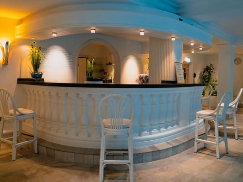 Wellnessbereich mit Poolbar und weißen Barhockern