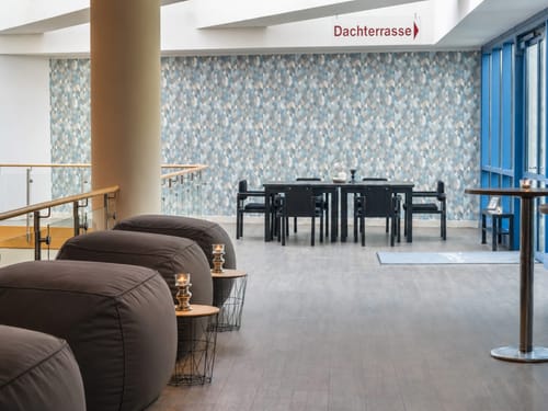 Loungebereich mit Sitzsäcken und Esstisch im modernen Hotel – Wegweiser zur Dachterrasse gut sichtbar im oberen Bildbereich