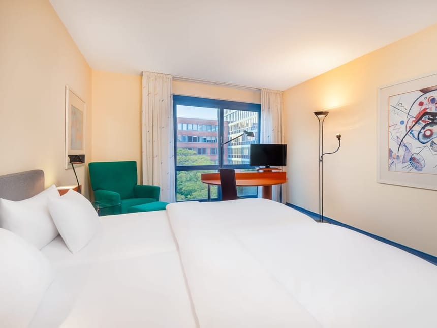 Helles Zimmer mit TV, Schreibtisch, Stuhl und Sessel