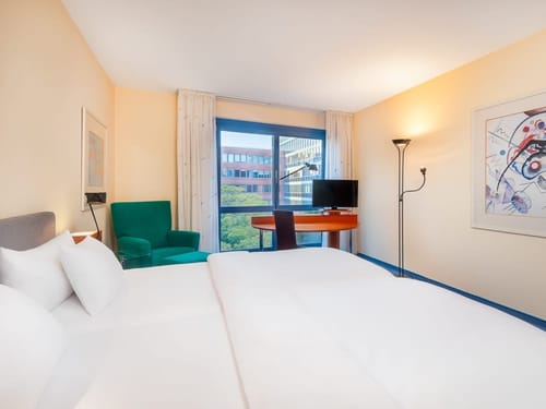 Helles Zimmer mit TV, Schreibtisch, Stuhl und Sessel