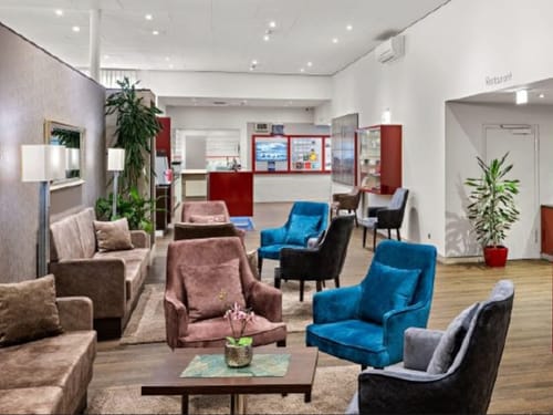verschieden farbige Sessel mit kleinen Tischen in der Lobby