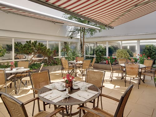 gedeckte Tische für das Frühstück im Wintergarten