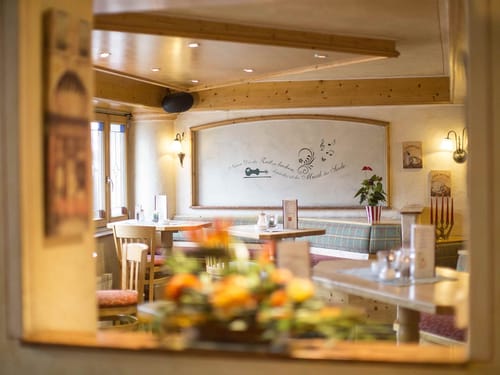 Gemütliches Café-Interieur mit Holztischen, Stühlen und Wanddeko.