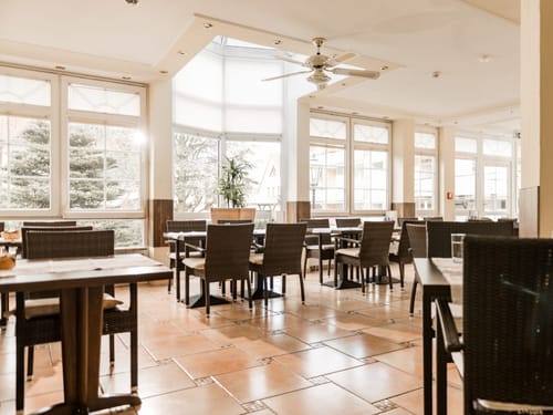 Modernes und lichtdurchflutetes Café mit Rattanmöbeln und großen Fenstern