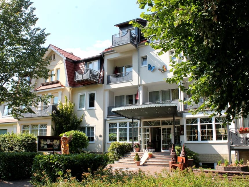 Außenansicht eines einladenden Hotels im Grünen mit blauem Himmel.