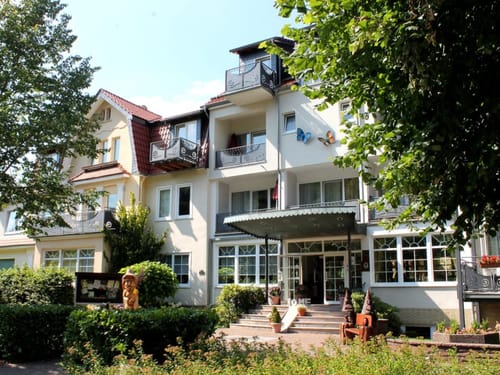 Außenansicht eines einladenden Hotels im Grünen mit blauem Himmel.