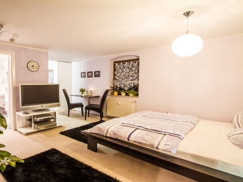 Schlaf und Wohnbereich mit Doppelbett, TV, kleinen Tisch und zwei Stühle