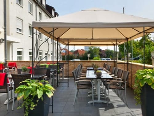 Große Terrasse mit Sonnenschirmen und einigen Sitzplätzen