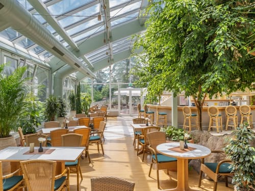 Lichtdurchflutetes Restaurant mit Glasdach und grünen Pflanzen