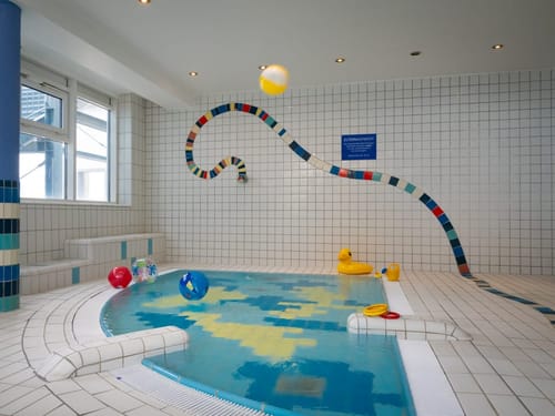Kinderbecken mit bunten Spielzeugbällen und Fliesenmuster