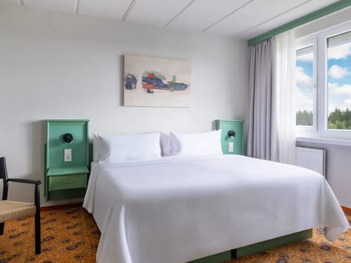Modernes Hotelzimmer mit komfortablem Doppelbett und großem Fenster
