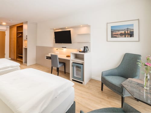 Großzügiges Hotelzimmer mit Doppelbett, Arbeitsbereich, Flachbild-TV, Minibar und komfortablem Sitzbereich