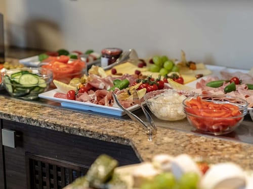 Speisenbuffet am Morgen mit einer Auswahl an Wurst und Käse, Gurke und Tomate