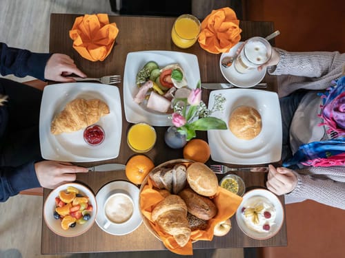gedeckter Frühstückstisch mit einer Auswahl an Brötchen, Saft, Kaffee, Kaffee sowie Wurst- und Käse