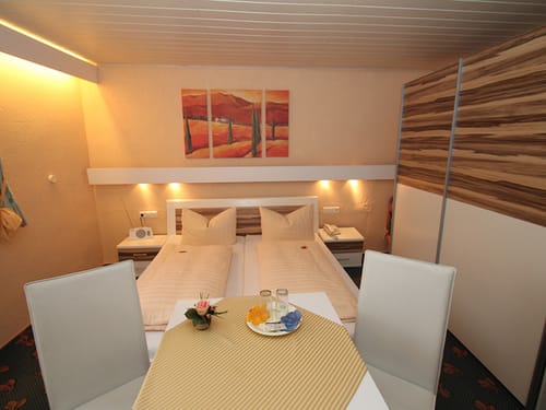 modernes Doppelzimmer mit Doppelbett zwei Stühlen und Tisch
