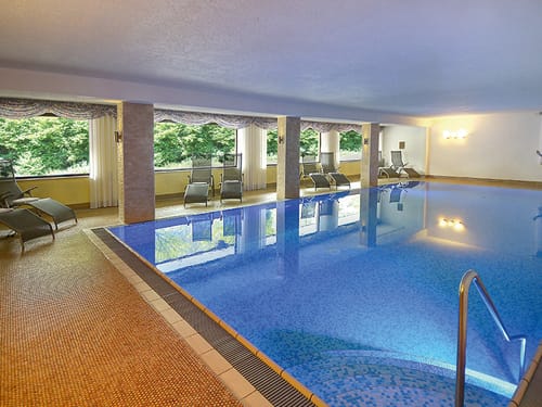Indoor Pool mit Relaxliegen am Rande im Wellnessbereich