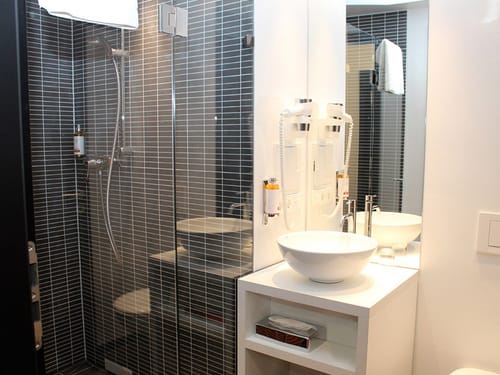 Badbereich mit Dusche, Föhn, Waschtisch und Spiegel