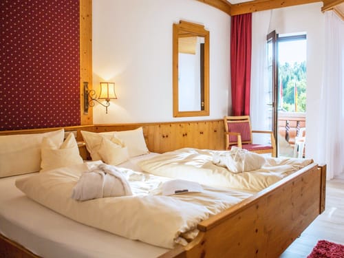 gemütliches Doppelzimmer mit Doppelbett, Sessel, Tisch und Balkon