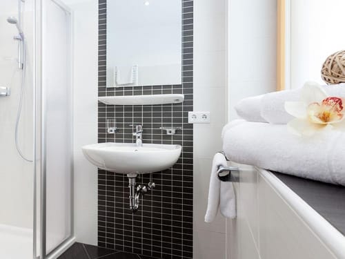 Badbereich mit Spiegel, Waschbecken, Ablage und Dusche