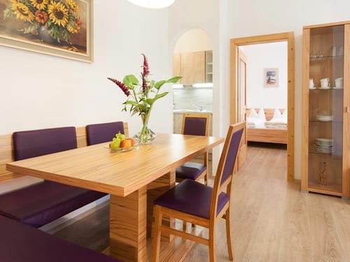 Essbereich mit Bank, Tisch, zwei Stühlen, Virtine und Blick in Schlafzimmer und Küche