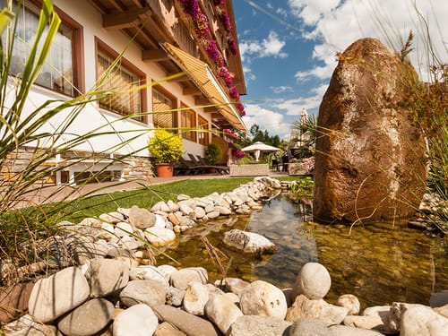 Gartenanlage mit Terrasse, Teich, Sonnenschirmen und Markise
