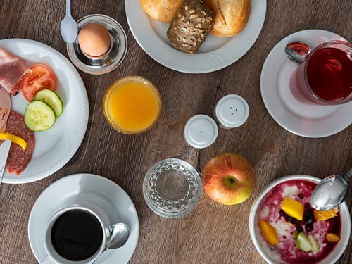 Tisch mit Brötchen, Salami, Tomaten, Gurken, Tee und Kaffee