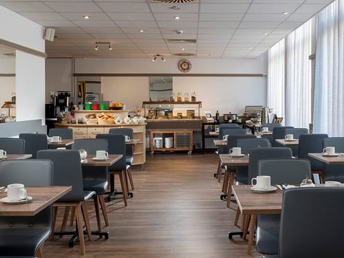 eingedeckte Tische für das Frühstück und Speisenbuffet