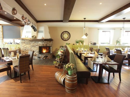 Hotel Restaurant mit eingedeckten Tischen und Kamin