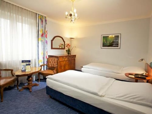 Zimmer mit Twinbett, Sesseln, Tisch, Kommode und Wandspiegel
