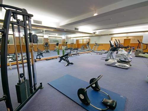 großer Fitnessraum mit verschiedenen Kardiogeräten