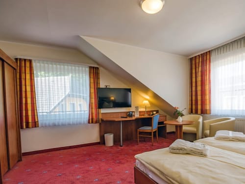 Doppelbett, zwei Sessel, Schreibtisch, Stuhl, TV und Kleiderschrank im Doppelzimmer
